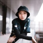 Home Portrait of a fashion-forward woman in a modern urban environment wearing a bucket hat.